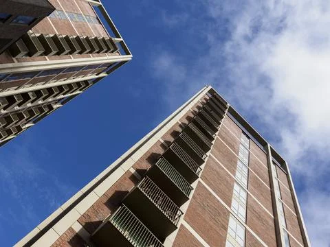 Low-angle view of two tall apartment buildings against a clear blue sky. Stock Photos