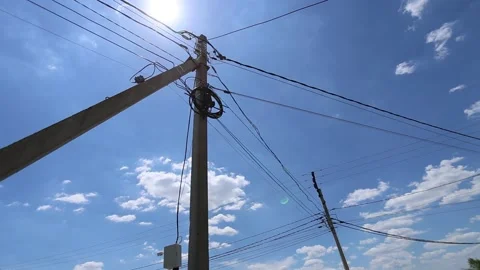 Low angle view of utility poles and overhead power lines crossing sunny blue sky Stock Footage 337937421
