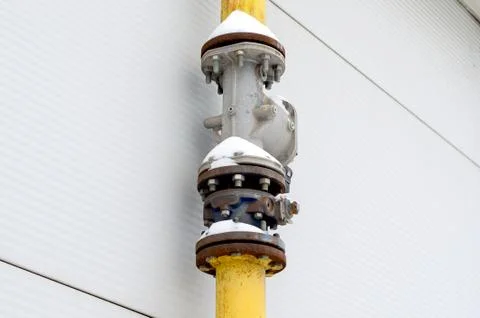 Low angle view of vertical gas pipe with  valve  nuts and bolts   against wal Stock Photos