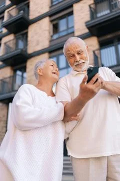 Low-angle view vertical portrait of cheerful beautiful senior couple with gray Stock Photos