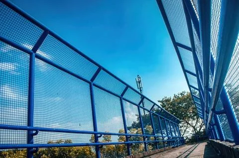 A low angle view of a vibrant blue pedestrian bridge featuring strong mesh .. Foto stock