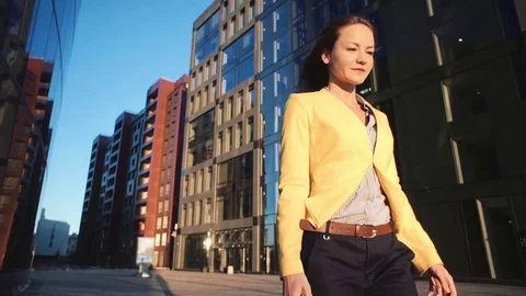 Low angle view video of Young beautiful girl in a yellow jacket near office with Stock Footage 71507507