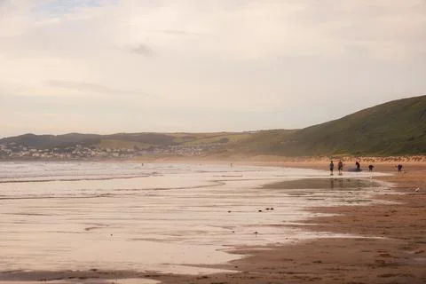 Low angle view at the waters edge on a uk beach with people surfing in the ba Stock Photos