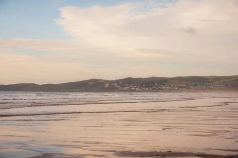Low angle view at the waters edge on a uk beach with people surfing in the ba Stock Photos