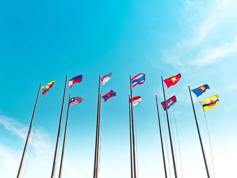 Low Angle View of Waving Flags of ASEAN Countries Against Blue Sky Foto stock