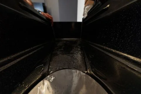Low angle view of wet plastic channel with hands and foil wrapped item Foto stock