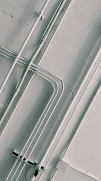 Low angle view of white electrical conduits, wire cables, and metal pipes. Stock Photos