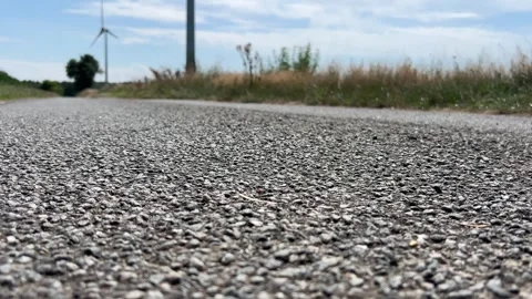 Low angle view of wind turbine on rural road under blue sky in 4K Stock Footage 339631064