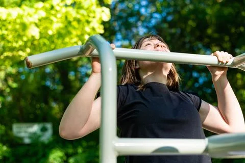 Low angle view of woman doing pull ups on street bar Stock-Fotos