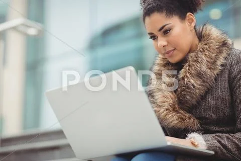 Low Angle View Of Woman With Laptop Against Building