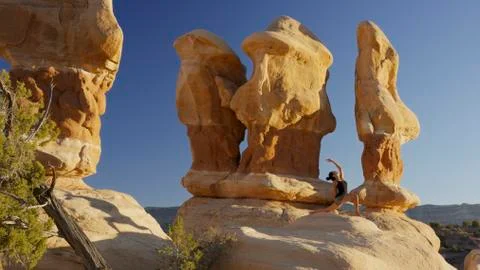 Low angle view of woman practicing yoga and meditating on rock formations in 库存照片