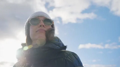 Low angle view woman in winter with sunglasses coat and hat in cold winter Stock Footage 289416705
