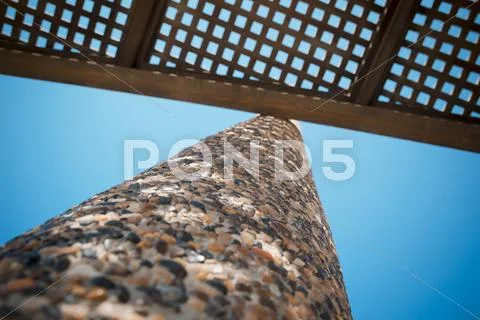 Low angle view on wooden shade of seating bench with pebble stone column Stock Photos