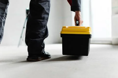 Low Angle View Of Worker Lifting Tool Case With Laser Level In Background Foto stock