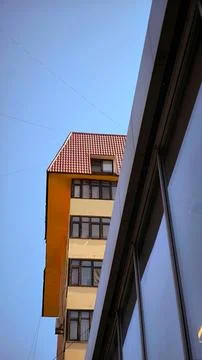 Low angle view of yellow building with red tiled roof. Fotos Stock