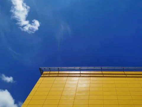 Low Angle View of Yellow Tiled Building Exterior Against Blue Cloudy Sky Stock Photos