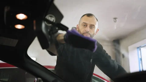 Low angle view of young car wash worker man, wearing protective gloves, cleaning Stock Footage 233894063