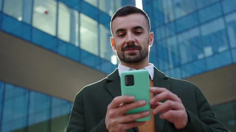 Low angle view of young Caucasian business man strolling relaxed looking at cell Stock Footage 315881128