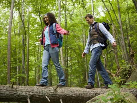 Low angle view of a young couple walking on a fallen tree Foto stock