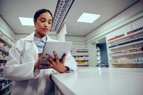 Low angle view of young female woman wearing labcoat working in chemist using Stock Photos