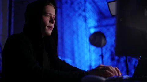 Low-angle view of young hacker male breaking into corporate data servers using Vídeos de archivo 198386682