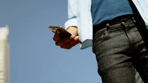 Low Angle View of a Young Man Using Mobile Phone in Urban City. Dolly Shot. S Stock Footage 123148863