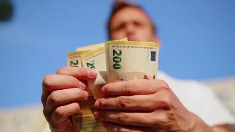 Low angle view of a young man counting 200 Euro banknotes outdoors. Guy che.. Stock Footage 335652713