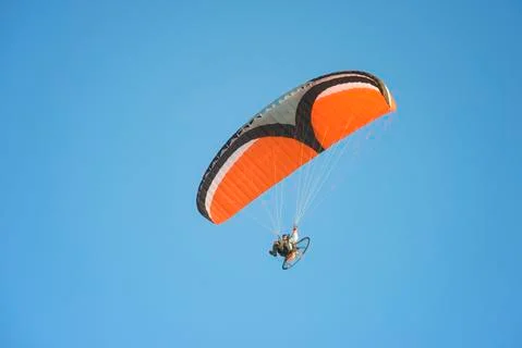 Low angle view of young man motor paragliding against clear sky Fotos de archivo