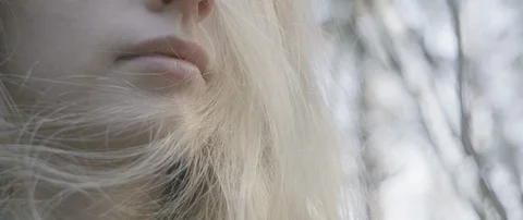 Low angle view of young woman's pink lips and blowing blonde hair Stock Footage 110388645