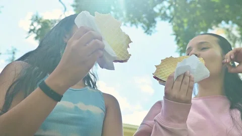 Low angle view of young women eating traditional Colombian food outdoors. 動画素材 332522377