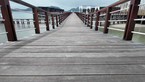 A low angle walking long wooden boardwalk stretching over the water Video stock 343393437