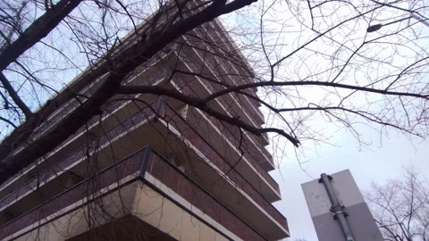 Low angle walking shot of Brutalist apartment balconies and winter tree in Video stock 331117519