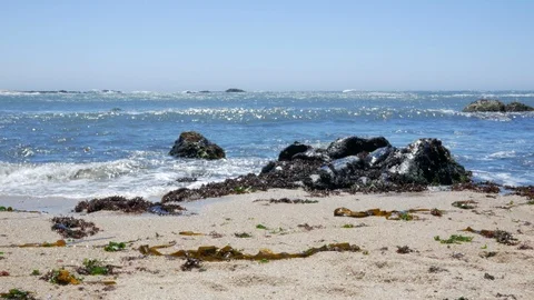 Low angle waves lapping on sandy beach with rocks Stock Footage 95124909
