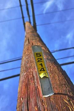 Low Angle Weathered Telephone Pole with Power Lines and Identification Tag Stock Photos