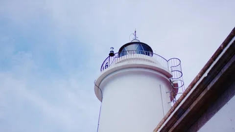 Low angle of white lighthouse lantern against blue cloudy sky, maritime beacon Видео 341579127