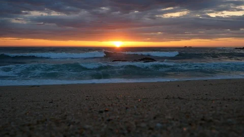Low angle wide shot over sandy beach at sunset with vivid sky Stock Footage 106646713