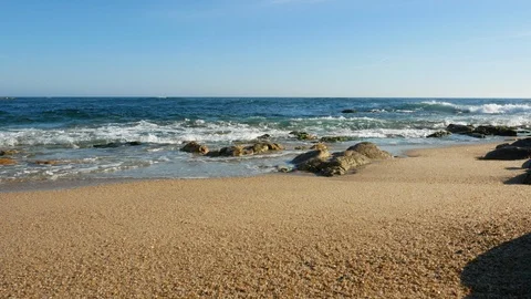 Low angle wide shot over sandy beach in summer as waves break on shore Stock Footage 108516913