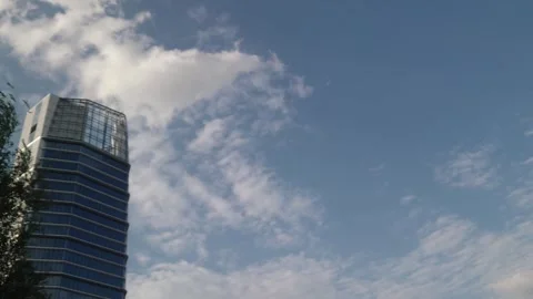 Low Angle Wide View Time Lapse of Clouds Moving Across Sky Above Glass Office 스톡 동영상 345041993