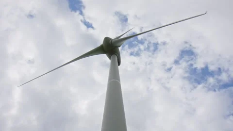 Low Angle of a Wind Turbine rotating against a cloudy sky on a windy summer day Stock Footage 243196226