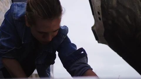 Low angle of a woman checking under a bonnet for routine checks on a Video stock 102441650