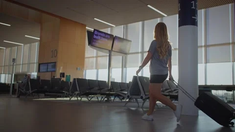 Low angle, Young female walks with luggage through the airport at sunrise 库存影片 220309928
