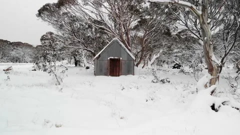 Low Angle Zoom Into Front of Snow Covered High Country Hut 4K Aerial Stock Footage 136718870