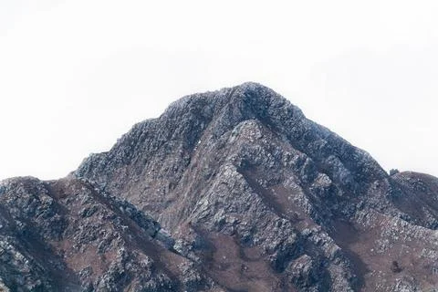 Low angle zoom in shot of a mountain peak with bright sky in the background. Stock Photos