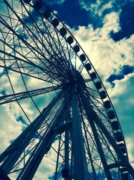 Low angled view of ferris wheel against sky with cumulus clouds Stock Photos