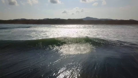 Low ascending flight into the sun over Playa Avellana exposing the tidal pool Stock Footage 90920068