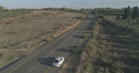 Low attitude tracking shot on a white sport car driving through open fields Stock Footage 100015148