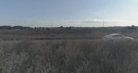 Low attitude tracking shot on a white sport car driving through open fields Stock Footage 100020082