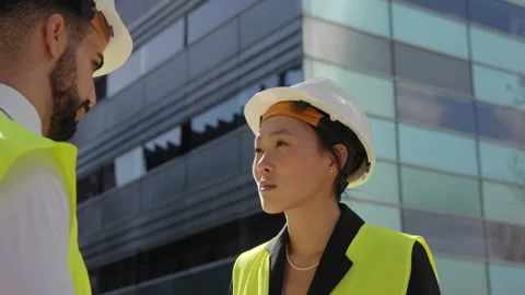 Low camera rotation two construction managers standing chatting concentrates Stock Footage 276960722