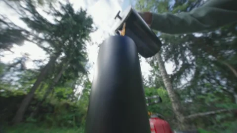 Low close up shot of coffee or tea being poured with forest in background in Stock Footage 338441516