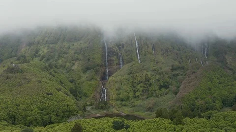 Low cloud covers mountain top. Waterfall streams on green steep slope. Aerial of 库存影片 119892090
